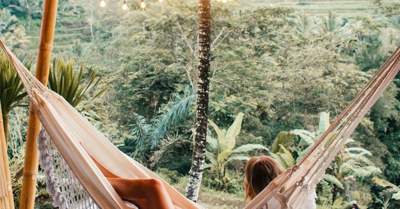 Rest Days - Slender woman resting in hammock under glowing garlands