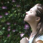 Breathing Techniques - Woman Closing Her Eyes Against Sun Light Standing Near Purple Petaled Flower Plant