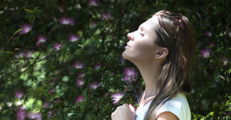 Breathing Techniques - Woman Closing Her Eyes Against Sun Light Standing Near Purple Petaled Flower Plant