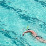 Swim Training - From above full length male swimmer in trunks swimming front crawl in big swimming pool