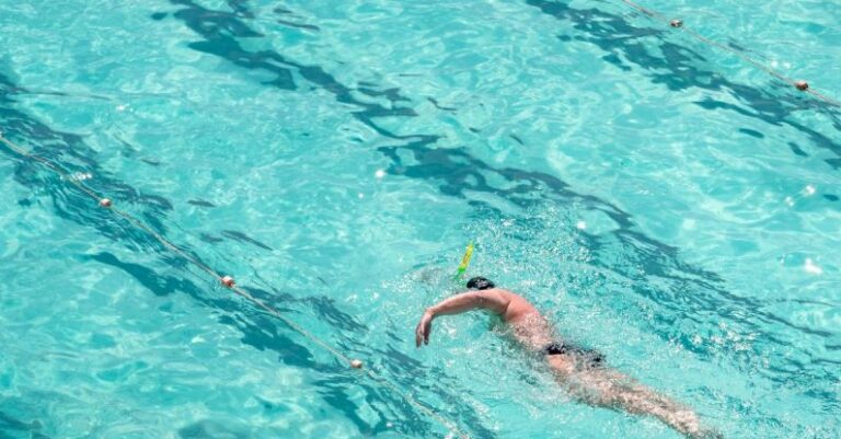 Swim Training - From above full length male swimmer in trunks swimming front crawl in big swimming pool