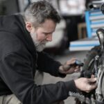 Bike Maintenance - Bearded man fixing motorcycle in workshop