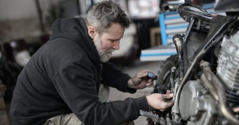 Bike Maintenance - Bearded man fixing motorcycle in workshop