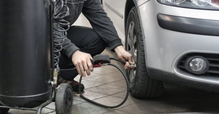 Tire Maintenance - Man in Black Jacket and Black Pants Sitting Near Silver Vehicle