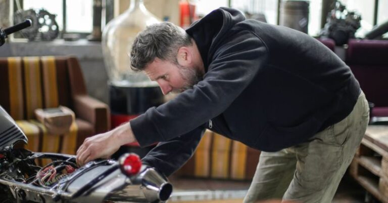 Bike Inspections - Professional adult bearded mechanic fixing motorcycle in workshop