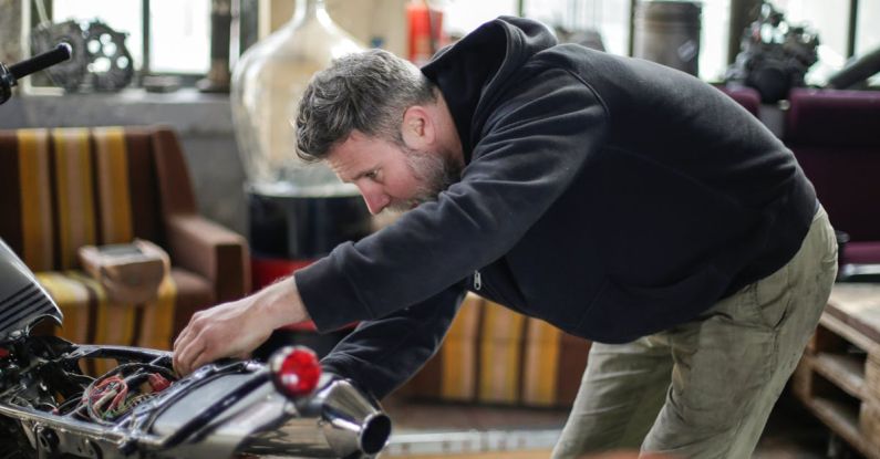 Bike Inspections - Professional adult bearded mechanic fixing motorcycle in workshop