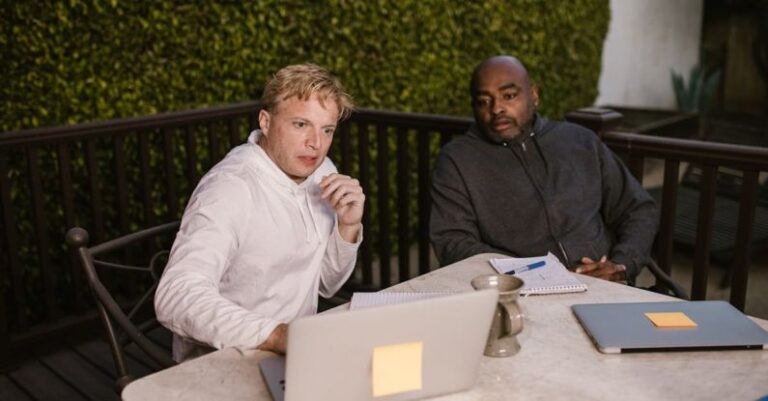 Training Gadgets - Men in Gray and White Sweater Sitting Near the Table while Looking at the Laptop