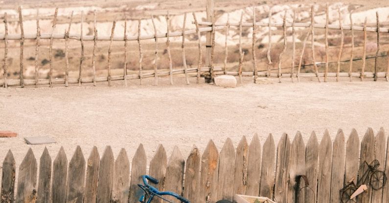 Bike Drafting - A blue bicycle leaning against a wooden fence