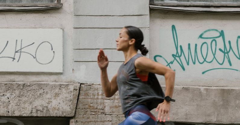 Speed Workouts - A Side View of a Woman Jogging on the Street