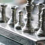 Tracking Progress - Classic metal chess board with set figurines designed with carved ornaments and placed on glass table in light room