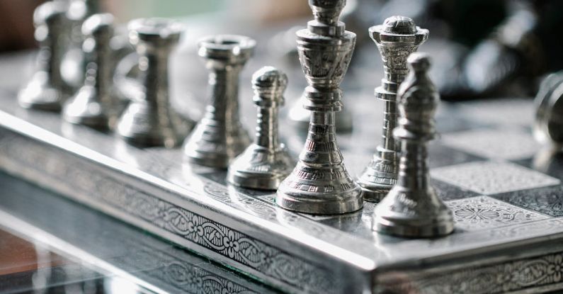 Tracking Progress - Classic metal chess board with set figurines designed with carved ornaments and placed on glass table in light room